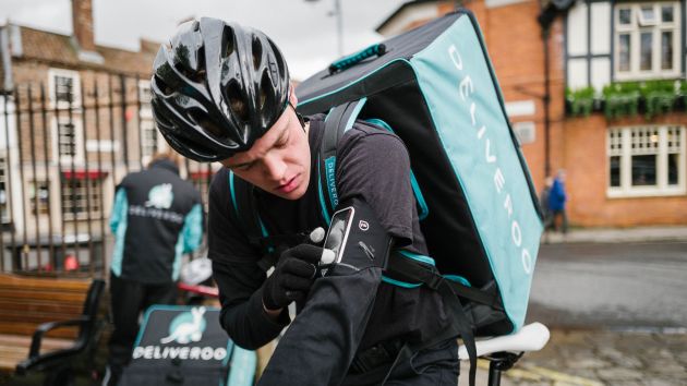 Deliveroo rider on a bicycle in a street with kit on