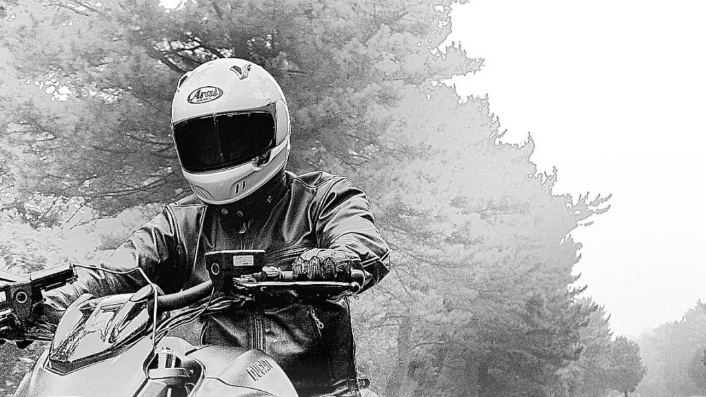 Motorcyclist riding through a forest road with arai helmet