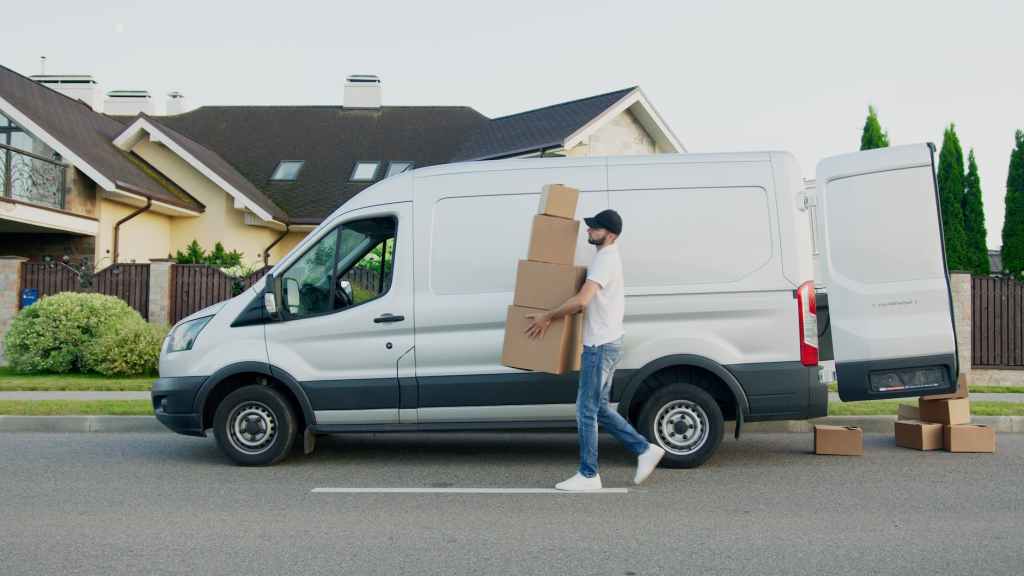 A delivery driver unloading parcels and boxes from the back of the van.