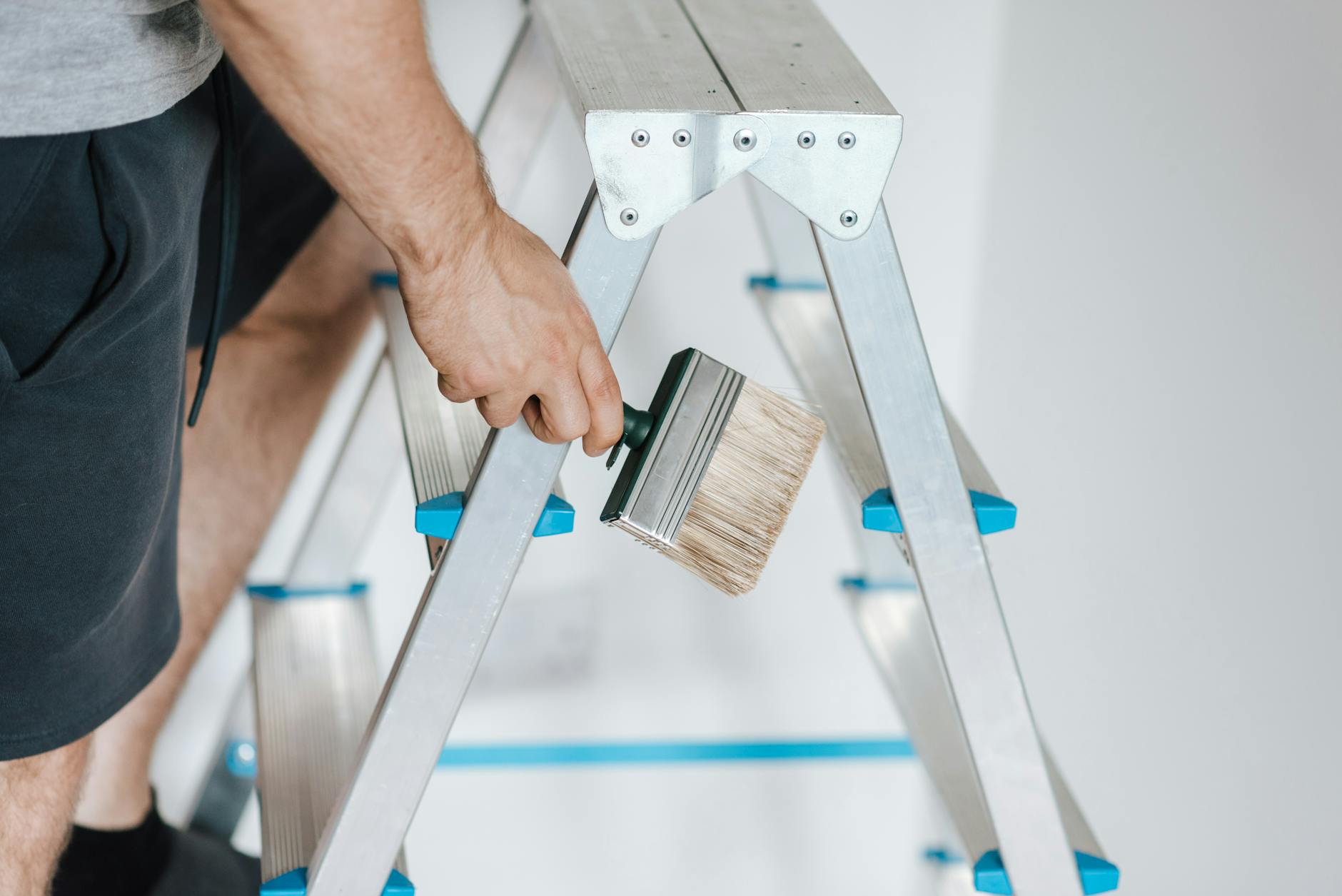 a person standing on a ladder painting the walls of a customer